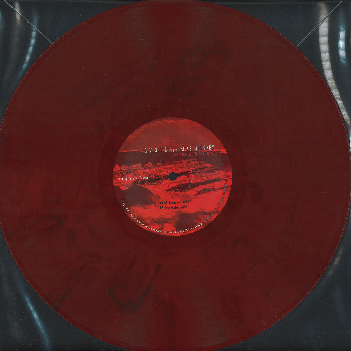Imagen del vinilo rojo jaspeado cv313 Plays Mike Huckaby – Our Life With The Wave mostrando el lado B completo con la etiqueta centrada y funda plástica translúcida.