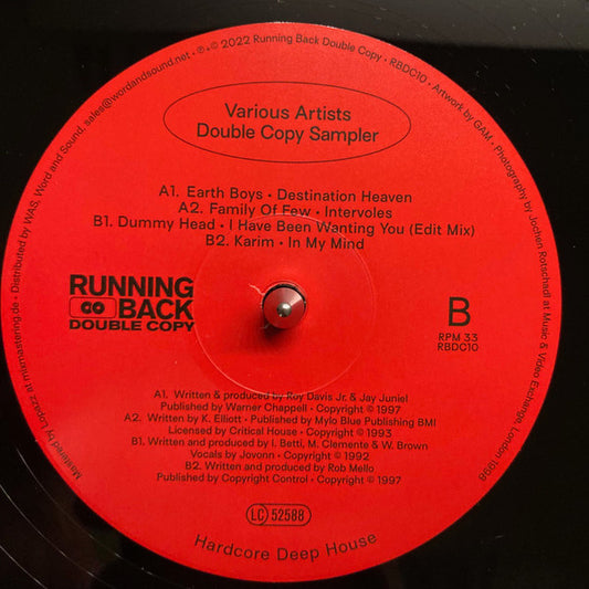 Portada trasera del vinilo Varios Artistas – Double Copy Sampler, publicado por Running Back Double Copy en formato 12". Lista de canciones con artistas como Earth Boys, Karim y Dummy Head. Diseño en rojo con tipografía clara y créditos de producción detallados.