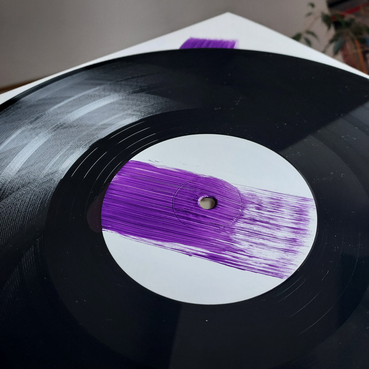 Primer plano del vinilo Ernesto – 1999 Love Story EP revelando su característico trazo violeta sobre el centro blanco del disco.