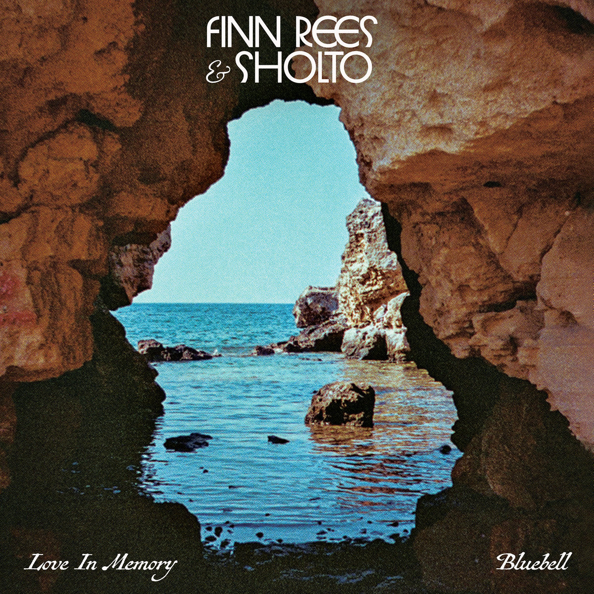 Portada del vinilo Finn Rees & Sholto – Love In Memory / Bluebell editado por Mr Bongo, mostrando una vista marítima a través de una cueva rocosa con tonos cálidos y el logo del disco centrado arriba.