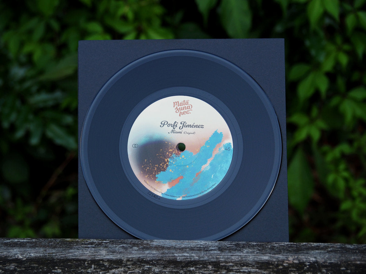 Vinilo Porfi Jiménez – Miami de Matasuna Records sobre una funda azul oscuro; edición 7" a 45 RPM con etiqueta lado A visible en primer plano.