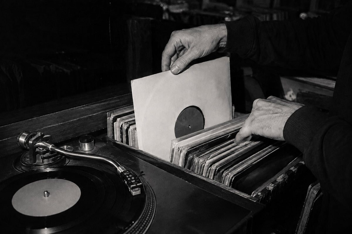 Una mano sostiene un disco de vinilo negro frente a un fondo amarillo vibrante, destacando el estilo único de nuestra tienda de discos de vinilo para DJs.